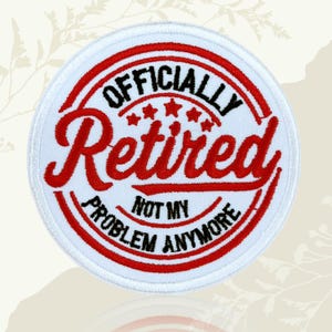 May include: A circular white patch with red and black text. The text reads "OFFICIALLY Retired" in a stylized font, with "NOT MY PROBLEM ANYMORE" below. The patch has a red border and star accents.