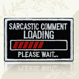 May include: Black rectangular patch with white embroidered border and text. The text reads "SARCASTIC COMMENT LOADING" above a red progress bar and "PLEASE WAIT..." below. The patch is likely for clothing or accessories.