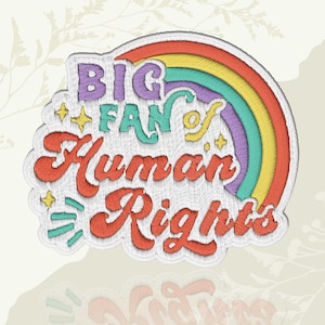 May include: Embroidered patch with the text "BIG FAN of Human Rights" in a colorful design. The patch features a rainbow, stars, and a decorative border. The text is in various colors, including purple, green, and orange.