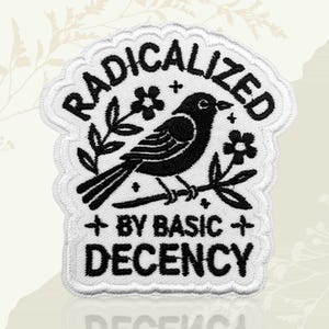 May include: Embroidered patch with a white border. The words "RADICALIZED" are arched across the top. A black bird perches on a branch with flowers. The text "BY BASIC DECENCY" is below the bird in black.