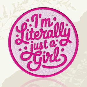 May include: A circular embroidered patch featuring the text "I'm Literally just a Girl" in vibrant pink script. The words are set against a pale pink backdrop, enclosed by a bold pink border.