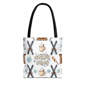 May include: White tote bag with black handles featuring a winter-themed pattern. The pattern includes skis, snowflakes, mugs of hot cocoa, a fireplace, and marshmallows on a stick. The words "winter vibes" are in the center.