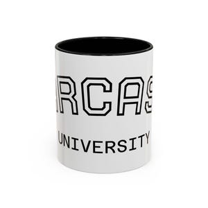 May include: White ceramic coffee mug with a black interior. The mug features the word "SARCASM" in bold, outlined black letters above the word "UNIVERSITY" in a similar font. A humorous gift idea.
