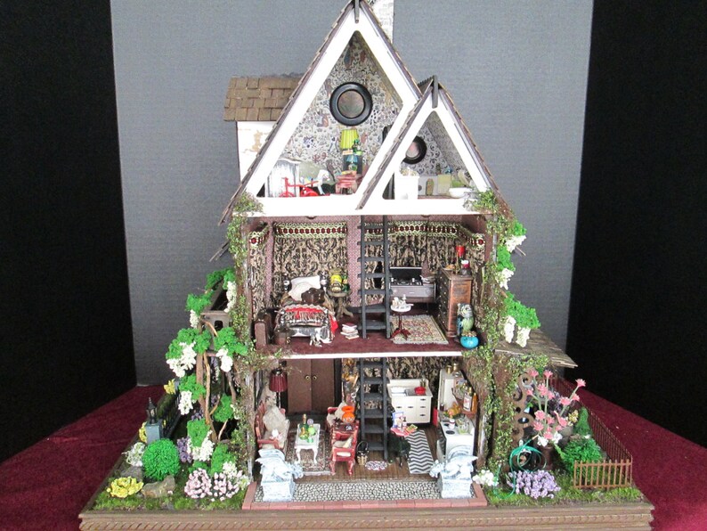 May include: A miniature dollhouse with a white exterior and a green ivy-covered facade. The dollhouse is open to reveal a multi-level interior with furnished rooms, including a living room, bedroom, and kitchen. The dollhouse is set on a base with a miniature garden.