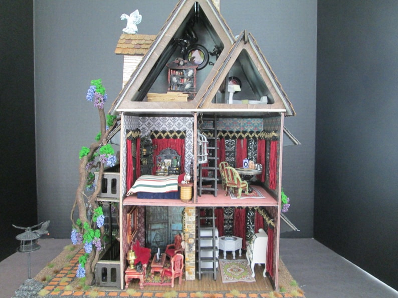 May include: A dollhouse with a whimsical design, featuring a wooden frame, a red roof, and a vine growing up the side. The interior is decorated with red curtains, a patterned wallpaper, and furniture. The dollhouse is open to reveal the interior rooms.