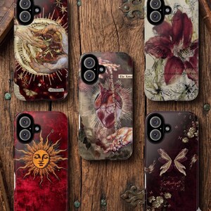 May include: A collection of phone cases with unique designs. The cases feature various artistic illustrations, including a sun face, a human heart, and floral and celestial motifs. The color palette includes deep reds, browns, and cream tones, with intricate details.