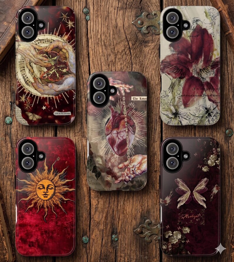 May include: A collection of phone cases with unique designs. The cases feature various artistic illustrations, including a sun face, a human heart, and floral and celestial motifs. The color palette includes deep reds, browns, and cream tones, with intricate details.