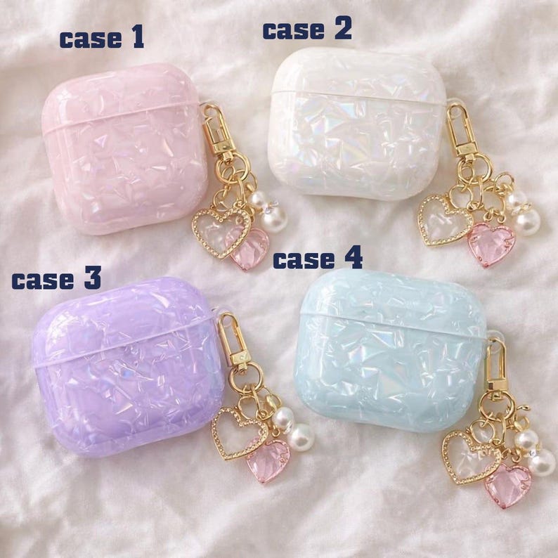 May include: Four iridescent AirPod cases in pink, white, purple, and blue, each with a gold-coloured keychain. The keychains have heart-shaped charms and faux pearls. The cases are labelled "case 1", "case 2", "case 3", and "case 4".