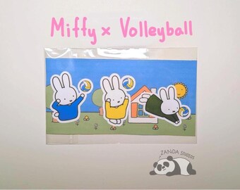 May include: A sticker sheet featuring three cartoon bunnies playing volleyball. The bunnies are wearing blue, yellow, and green outfits. The background shows a blue sky, a house, and a sun. The text "Miffy x Volleyball" is written in pink.