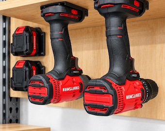 Può includere: Due trapani a batteria Craftsman neri e rossi montati capovolti sotto una mensola in legno, con due batterie aggiuntive fissate al pannello a parete in legno dietro i trapani, dotati di impugnature testurizzate.