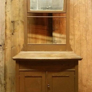 May include: A vintage wooden cabinet with a mirrored top and two doors. The cabinet is painted a dark brown color and has a decorative carved top.