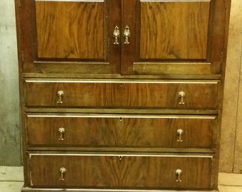 Puede incluir: Un aparador de madera marrón oscuro con cuatro cajones y un armario con dos puertas. El aparador tiene tiradores de latón y una base ligeramente curvada.