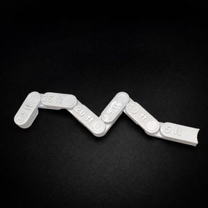 May include: A white, articulated measuring tool with segments labeled from 5 ft to 30 ft. The tool is zig-zagged, with each segment connected by a hinge. The numbers are in a sans-serif font.