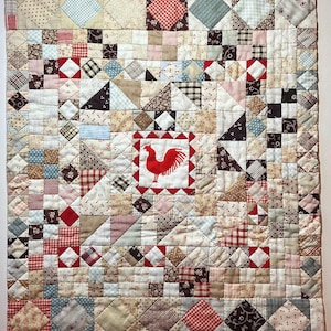 May include: Handmade patchwork quilt with a rooster motif. The quilt features a variety of fabric patterns in red, white, blue, and brown. The center square showcases a red rooster. The quilt is approximately 40 inches by 40 inches.
