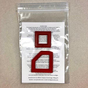 Può includere: Timbri in gomma rossa con retro in schiuma adesiva, confezionati in un sacchetto di plastica trasparente. I timbri hanno la forma di una casa e di un quadrato. Le istruzioni per l'uso dei timbri sono stampate su un foglio di carta bianca.