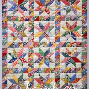 May include: A patchwork quilt with a star design, featuring a vibrant mix of fabrics in red, blue, green, yellow, and purple. The quilt has a cream-coloured background and a patterned border. The text "jeanneke.com" is visible.
