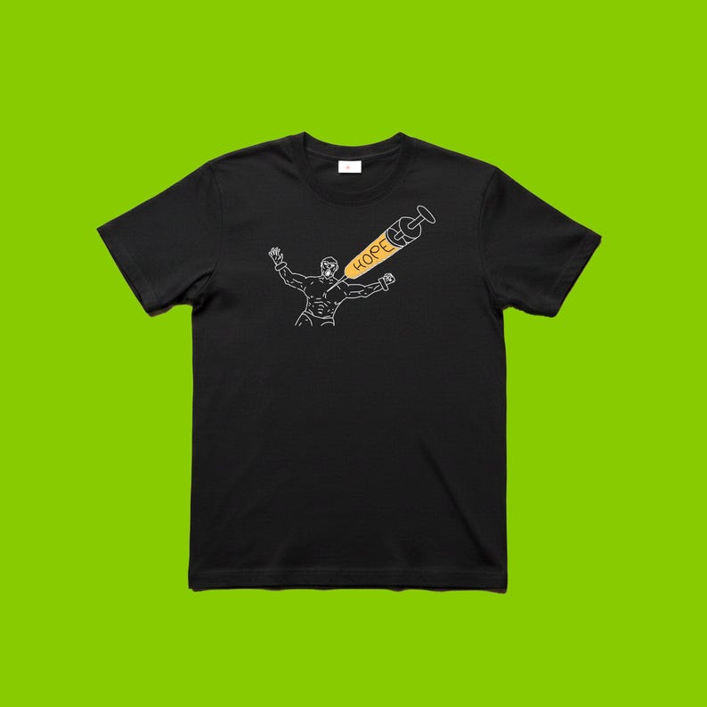 May include: Black t-shirt featuring a white outline illustration of a person with arms raised, and a syringe with the word "HOPE" in yellow. The syringe is angled towards the person. The t-shirt is displayed on a green background.