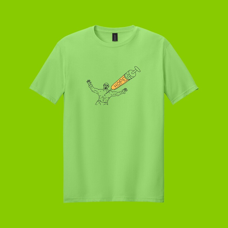May include: Lime green t-shirt featuring a black line drawing of a person with arms outstretched, pierced by a syringe. The syringe is orange with the word "HOPE" printed on it. The shirt is a solid color.