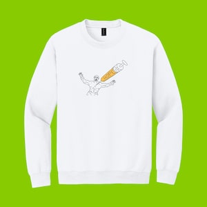 May include: White crewneck sweatshirt featuring a black and orange graphic. The graphic depicts a person with arms raised, with a syringe labeled "HOPE" piercing their chest. The design is a minimalist line drawing style.