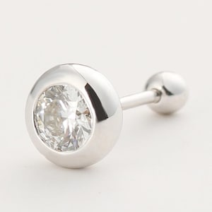 May include: A single, silver-toned earring with a clear, sparkling gemstone set in a bezel. The earring features a post with a small, round ball on the end. The design is simple and elegant, suitable for various occasions.