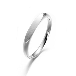 May include: A silver ring with a brushed, rectangular top and a smooth, rounded band. The ring is set against a white background, highlighting its polished finish and minimalist design. The ring's design is simple and elegant.
