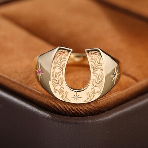 Anillo de herradura de oro de 14 quilates con grabado de pluma y gemas en forma de estrella.