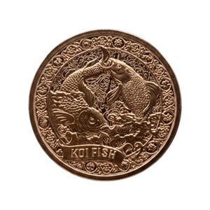 May include: A bronze-colored coin featuring three koi fish in a detailed, swirling design. The coin's edge has a decorative border, and the words "KOI FISH" are inscribed on a banner across the bottom.