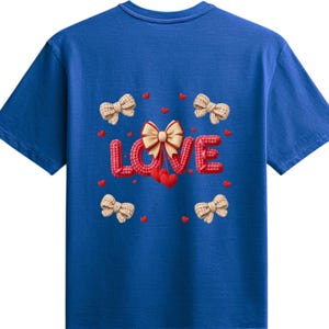 May include: Royal blue t-shirt featuring a decorative design. The word "LOVE" is spelled out in red, textured letters, with a cream-coloured bow in the centre. Small red hearts and cream-coloured bows are scattered around the word.