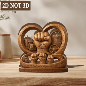 May include: A wooden Trucker Dad sculpture with a heart-shaped design. It features a fist, trucks, a steering wheel, and the text "Trucker Dad." The base includes the text "To the road, you're a legend. To us, you're home."