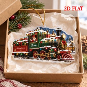 May include: A 2D flat Christmas ornament shaped like a steam locomotive train. The train is green and red with gold accents, featuring Santa Claus in the cabin, the text 'James' and 'Christmas Express', and colorful holiday lights.
