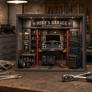 May include: A miniature diorama of an auto repair shop titled MIKE'S GARAGE AUTO REPAIR & CUSTOMS. The scene features a car on a lift, a workbench with tools, a tool chest, and wall signs reading FIX IT FAST DRIVE IT PROUD and BUILT Not Bought.