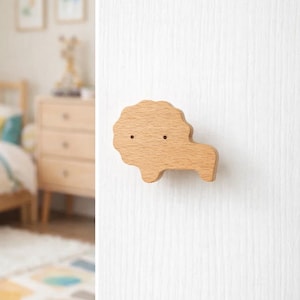 May include: A wooden lion-shaped wall hook. The hook is made of light-colored wood and features two small, dark dots for eyes. The lion's mane is textured, and the hook extends from the body. Ideal for a child's room.