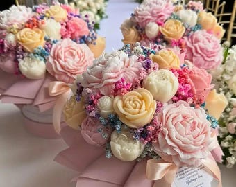 May include: Several floral arrangements featuring pastel-colored roses, peonies, and other flowers. The bouquets are arranged in round, pink boxes and tied with pink ribbons. The flowers are in shades of pink, white, and yellow.