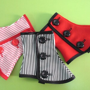 May include: Three decorative collar accessories in red, black and white. One is red with black trim and buttons, another is black and white striped, and the third is red and white striped. Each has button closures.
