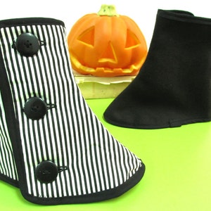 May include: Two decorative boot covers, one black and white striped with black buttons, the other solid black. A carved orange pumpkin sits in the background. The boot covers are likely for Halloween or costume use.