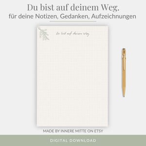 May include: A digital download notepad with a dot grid pattern. The notepad has the text "Du bist auf deinem Weg" and "für deine Notizen, Gedanken, Aufzeichnungen". A gold pen rests on the right side. The bottom of the image says "MADE BY INNERE MITTE ON ETSY" and "DIGITAL DOWNLOAD".