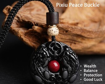 May include: A black circular pendant featuring a Pixiu design with a central red bead, suspended from a black braided cord. The piece includes a dark wooden bead and a speckled light-colored bead. Text reads: Pixiu Peace Buckle, Wealth, Balance, Protection, Good Luck.