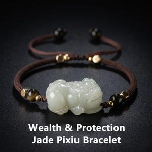 Peut inclure: Un bracelet Pixiu en jade avec un cordon marron et des détails dorés. La pièce maîtresse est une figurine Pixiu en jade sculpté, symbole de richesse et de protection. Le bracelet porte l'inscription "Wealth & Protection Jade Pixiu Bracelet".