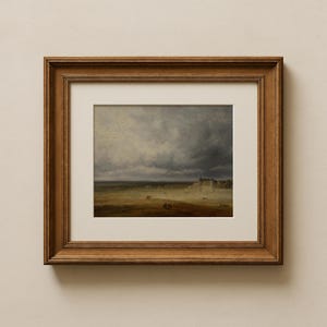 May include: A framed landscape painting featuring a field under a stormy sky. The artwork is set within a gold-toned wooden frame and a white mat. The painting depicts a rural scene with a building in the distance.
