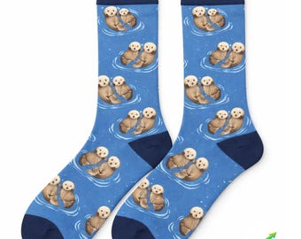 May include: A pair of blue socks with a pattern of otters floating in water. The socks have navy blue heels, toes, and cuffs. The otters are brown and white, and the water is light blue with white highlights.