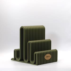 Könnte beinhalten: Ein Set aus drei Keramikbechern mit gesprenkelter, matter Oberfläche. Die Becher sind in Grau-, Weiß- und Schwarztönen gehalten. Jeder Becher hat ein schlichtes, minimalistisches Design, ideal für Kaffee oder Tee. Die Becher sind aufeinander gestapelt.