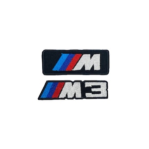 Può includere: Due toppe ricamate con il logo BMW M. La toppa superiore è rettangolare con il logo M in bianco e i colori BMW blu, rosso e blu. La toppa inferiore ha il logo M3 in bianco.