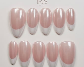 Może przedstawiać: Zestaw dziesięciu sztucznych paznokci z wzorem manicure francuskiego. Paznokcie mają błyszczącą, jasnoróżową bazę z białą końcówką. Marka "IRIS NAILAZY" jest widoczna na górze.