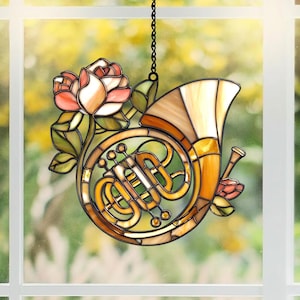 May include: A stained glass French horn, featuring a rose and leaves. The horn is in shades of brown and gold, with a bell-shaped end. The rose is pink and white, with green leaves. A black chain is attached for hanging.