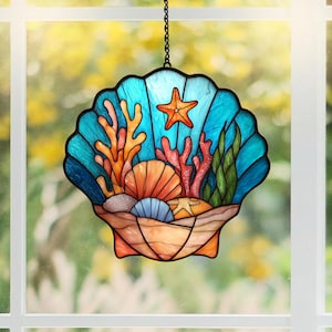 Puede incluir: Atrapasoles de vidriera con forma de concha marina y escena oceánica. Presenta una concha azul, una estrella de mar naranja y corales coloridos. El diseño incluye diversas conchas y algas marinas, creando una detallada exhibición submarina. Cuelga de una cadena negra.