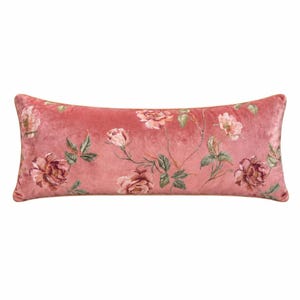 May include: A rectangular lumbar pillow featuring a soft pink velvet fabric base. The surface is decorated with a repeating floral pattern of blooming roses in shades of deep pink and muted green leaves, spread across the entire front face.
