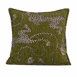 May include: A square throw pillow featuring a textured olive green fabric base with a repeating pattern of leaping leopards. The leopards are depicted in a cream color with black spots and outlines, showcasing a detailed feline print.