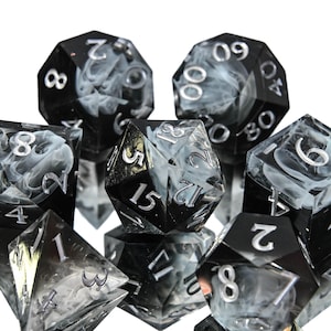 May include: A collection of polyhedral dice in various shapes. The dice are black with a swirling white pattern and silver numbering. The set includes a variety of dice for tabletop gaming.