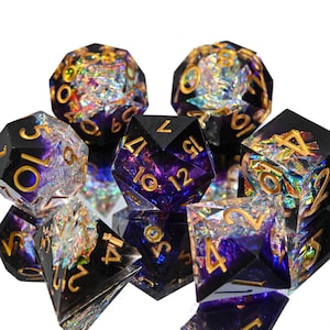 May include: A collection of polyhedral dice in various shapes, including D4, D6, D8, D10, D12, and D20. The dice are black with gold numbering and iridescent, colorful inclusions. The dice are designed for tabletop role-playing games.