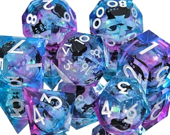Puede incluir: Un conjunto de dados de múltiples caras en tonos azules, morados y transparentes. Cada dado presenta números blancos y una silueta de gato negro. Los dados están diseñados para juegos de rol de mesa.